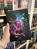 Das Cover zeigt mittig eine Phiole mit einer pinken Flüssigkeit. Der Titel steht mittig auf dem Cover, der Name der Autorin sdarüber. Im Hintergrund sind blau-grün-rosa schillernde Schuppen abgebildet. Die Phiole wird umrundet von zwei kleinen Wolkenmonstern, goldenen Federn und Krakenarmen. Der Rest des Hintergrunds ist schwarz.