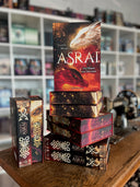 Das Bild zeigt einen Stapel von "Asrai - Die Magie der Drachen". Das Cover ist dabei direkt auf den Betrachter gerichtet und der Farbschnitt sowie der Buchrücken bei den liegenden Büchern sichtbar.