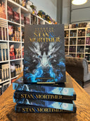 Das Bild zeigt einen Stapel von "Stan und Mortimer". Das Cover ist dabei direkt auf den Betrachter gerichtet und der Farbschnitt sowie der Buchrücken bei den liegenden Büchern sichtbar.