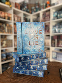 Das Bild zeigt einen Stapel von "Love or Lie". Das Cover ist dabei direkt auf den Betrachter gerichtet und der Farbschnitt sowie der Buchrücken bei den liegenden Büchern sichtbar.
