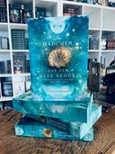 Das Bild zeigt einen Stapel von "Das Mädchen, das dem Meer gehört". Das Cover ist dabei direkt auf den Betrachter gerichtet und der Farbschnitt sowie der Buchrücken bei den liegenden Büchern sichtbar.