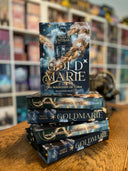 Das Bild zeigt einen Stapel von "Goldmarie". Das Cover ist dabei direkt auf den Betrachter gerichtet und der Farbschnitt sowie der Buchrücken bei den liegenden Büchern sichtbar.