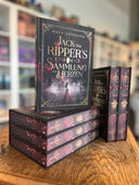 Das Bild zeigt einen Stapel von "Jack the Ripper's Sammlung der Herzen". Das Cover ist dabei direkt auf den Betrachter gerichtet und der Farbschnitt sowie der Buchrücken bei den liegenden Büchern sichtbar.