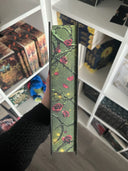 Das Bild zeigt den Farbschnitt von "Die Erben des Feenfluchs" Er zeigt rote Rosenblüten und Ranken auf grünem Untergrund.
