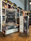 Das Bild zeigt einen Stapel von "House of Zodiac - Sternenstaub". Das Cover ist dabei direkt auf den Betrachter gerichtet und der Farbschnitt sowie der Buchrücken bei den liegenden Büchern sichtbar.