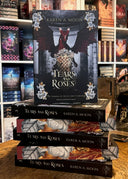 Das Bild zeigt einen Stapel von "Tears and Roses". Das Cover ist dabei direkt auf den Betrachter gerichtet und der Farbschnitt sowie der Buchrücken bei den liegenden Büchern sichtbar.