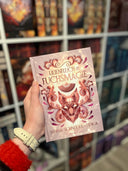 Das Bild zeigt das Buch "Lilienfluch & Fuchsmagie" von vorn. Das Cover ist dabei direkt auf den Betrachter gerichtet; es zeigt einen rosafarbenen, metallischen Fuchskopf umgeben von passenden Ornamenten auf hellem Untergrund.