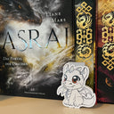 Das Produktbild zeigt ein Magnetlesezeichen mit einem weißen Babydrachen. Im Hintergrund ist das Buch "Asrai - Das Portal der Drachen" abgebildet. Auf dem Cover sind ein schwarzer und ein weißer Drache abgebildet. 