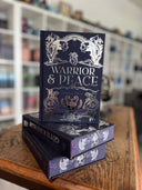 Das Bild zeigt einen Stapel von "Warrior & Peace" (Band 1). Das Cover ist dabei direkt auf den Betrachter gerichtet und der Farbschnitt sowie der Buchrücken bei den liegenden Büchern sichtbar.
