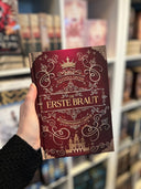 Das Cover zeigt mittig den Titel des Buches. Oberhalb des Titels steht der Name der Autorin, darüber befindet sich eine goldene Krone. In den Ecken sind goldene Schnallen abgebildet und im unteren Viertel ist ein goldenes Schloss zu sehen. Die Grundfarbe ist Rot. Der Farbschnitt ist rot mit goldenen Verzierungen darauf.