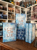 Das Bild zeigt einen Stapel von "Love or Lie". Das Cover ist dabei direkt auf den Betrachter gerichtet und der Farbschnitt sowie der Buchrücken bei den liegenden Büchern sichtbar.