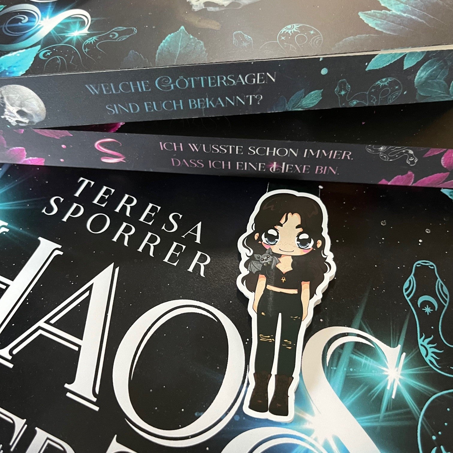 Das Produktbild zeigt ein Magnetlesezeichen mit einer schwarzhaarigen Frau in einem schwarzen Croptop, zerissener schwarzer Hose und dunklen Boots. Um ihren Hals trägt sie eine Kette mit einem Anch als Anhänger und auf ihrer Schulter sitzt eine Fledermaus. Gezeichnet ist das Lesezeichen im Anime-Stil.