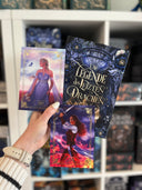 Das Bild zeigt, wie eine Hand das Buch "Die Legende des letzten Drachen" von Maya Shepherd und die beiden Charakterkarten mit den beiden Hauptfiguren des Buches hält. 