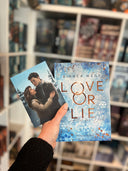 Das Bild zeigt das Buch "Love or Lie" von Bianca Wege und die passende Charakterkarte dazu, auf der die beiden Hauptpersonen in inniger Umarmung abgebildet sind. 