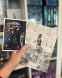 Auf dem Bild ist eine Hand abgebildet, welche das Buch "Magie aus Gift und Silber" und die dazugehörige Charakterkarte hält. Auf der Karte sind die beiden Protagonisten Rücken an Rücken abgebildet. Sie tragen Lederrüstung und sind mit einem Dolch und einem Schild ausgerüstet. Sie werden von einer großen, blauen Schlange umrundet. Im Hintergrund ist ein griechischer Torbogen abgebildet.