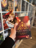 Das Bild zeigt das Buch "Noble Match" von Nicole Knoblauch und die passende Charakterkarte dazu, auf der die beiden Hauptpersonen in inniger Umarmung abgebildet sind. 
