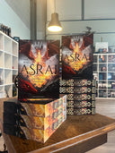 Das Bild zeigt zwei Stapel der Softcover von "Asrai - Das Herz der Drachen" nebeneinander. Das Cover ist dabei direkt auf den Betrachter gerichtet und der Farbschnitt sowie der Buchrücken bei den liegenden Büchern sichtbar.