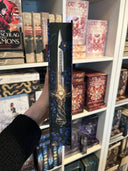 Das Bild zeigt den Farbschnitt von "Die Legende des letzten Drachen" Er zeigt eine Klinge mit goldenen Lichtelementen auf dunkelblauen Blüten.