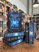 Das Bild zeigt einen Stapel von "Seele aus Eis". Das Cover ist dabei direkt auf den Betrachter gerichtet und der Farbschnitt sowie der Buchrücken bei den liegenden Büchern sichtbar.
