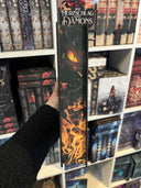 Das Bild zeigt den Farbschnitt von "Im Schatten der Drachenflamme" Er zeigt das Auge eines Drachen in der Dunkelheit, platziert über orangefarbenem Feuer.
