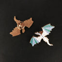 Das Produktbild zeigt rechts einen Pin in Form eines fliegenden Drachen in den Farben Blau, Türkis und Weiß. Links daneben sieht man die Rückseite des Pins.