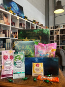 Das Produktbild zeigt vorn eine geöffnete Drachenpost in blauem Schuppen-Design. Man sieht den in den Boxdeckel geklebten Brief zum Thema #mytime und in der Box zum Thema passende Goodies - Süßigkeiten und andere Kleinigkeiten. Im Hintergrund sieht man die Bücherregale des Verlagsladens. 