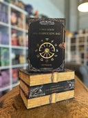 Das Bild zeigt einen Stapel von "Das zerbrochene Rad - Dämmerung". Das Cover ist dabei direkt auf den Betrachter gerichtet und der Farbschnitt sowie der Buchrücken bei den liegenden Büchern sichtbar.