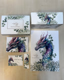 Das Bild zeigt eine Buchbox, ein Poster, die "Für Dich"-Karte, ein Lesezeichen und ein eingepacktes Buch. Alles ziert ein Drache in Lila- und Grüntönen, der von Eukalyptus-Blättern umgeben ist. 