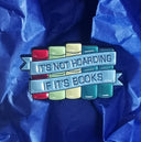 Das Produktbild zeigt einen Pin mit fünf Büchern in rot, grün, gelb und blau. Eine blaue Banderole mit der Aufschrift "it's not hoarding if it's books" umrahmt die Bücher.