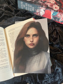 Das Page Overlay zeigt das Porträt der weiblichen Hauptfigur des Buches "Magic of Sins". Kaya trägt ihr braunes, langes Haar offen und ein graues Oberteil mit hochgeschlossenem Kragen.