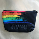 Das Produktbild zeigt ein schwarzes Täschchen mit einem gemalt wirkenden Regenbogen und dem Schriftzug be proud of you darunter. Der Reißverschluss befindet sich auf der oberen Seite.