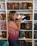 Das Bild zeigt die Autorin Liane Mars, welche vor einem Bücherregal steht und einem weißen Stoffdrachen einen Kuss auf die Stirn drückt.