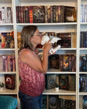 Das Bild zeigt die Autorin Liane Mars, welche vor einem Bücherregal steht und einem weißen Stoffdrachen einen Kuss auf die Stirn drückt.