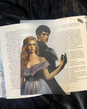 Das Page Overlay zeigt die Hauptfiguren aus "Das Geheimnis der Rabenblüter". Sera trägt ein fliederfarbenes Kleid und offnes blondes Haar. Valerian trägt dunkle Kleidung und schwarze Federn an den Schultern. Sie stehen Rücken an Rücken, als würden sie tanzen. Ihre Hände berühren sich.