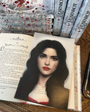 Das Page Overlay zeigt das Porträt der weiblichen Hauptfigur des Buches "Rosenrot". Rosenrot hat schwarze, offene Haare, sehr helle Haut und dunkelrote Lippen. 