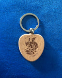 Das Produktbild zeigt einen Schlüsselanhänger aus Holz in Herzform. Auf ihm ist das Bild eines Drachen, der auf einem Bücherstapel sitzt, sowie der Schriftzug "Im Herzen ein Drache" zu sehen.