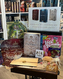 Auf dem Bild sieht man im Mittelpunkt das Buch "Die fünfte Braut" in der Schmuckausgabe und drumherum die diversen Extras, die Teil der Bücherbox sind.