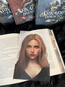 Das Page Overlay zeigt das Porträt der weiblichen Hauptfigur des Buches "Arkadien erwacht". Rosa hat schulterlanges, blondes Haar. Sie trägt ein dunkles Oberteil mit V-Ausschnitt. 