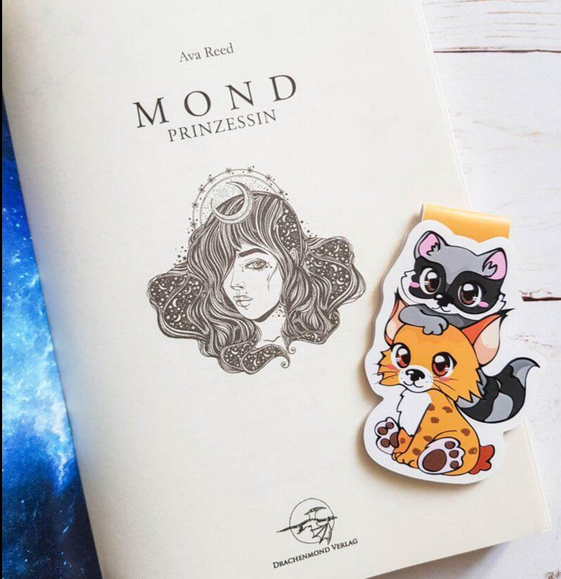 Das Produktbild zeigt einen Magnetlesezeichen mit einem kleinen Luchs über dessen Kopf ein kleiner Waschbär schaut.