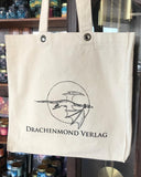 Das Produktbild zeigt einen hellen Leinenbeutel, auf dem mittig in schwarz das Verlagslogo (ein fliegender Drache vor einem Vollmond) abgebildet ist. Darunter steht in schwarzen Großbuchstaben "Drachenmond Verlag".