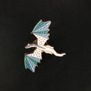 Das Produktbild zeigt einen Pin in Form eines fliegenden Drachen in den Farben Blau, Türkis und Weiß.
