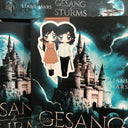 Das Produktbild zeigt ein Magnetlesezeichen mit den beiden Protagonistinnen des Buches "Der Gesang des Sturms". Eine Frau trägt ein braunes kurzes Kleid, hat einen Köcher mit Pfeilen auf dem Rücken und hält einen Boden in der Hand. Die zweite Frau trägt ein helles Oberteil und eine schwarze Hose. Sie hat ein Schwert in ihrer Hand. Gezeichnet ist das Lesezeichen im Anime-Stil.