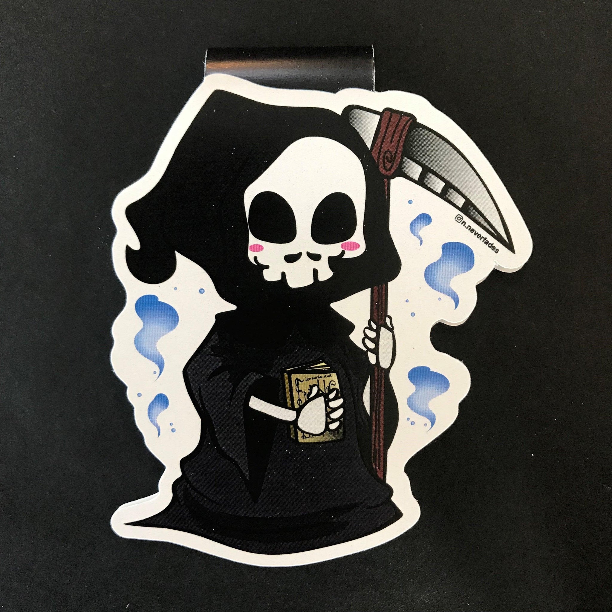 Das Produktbild zeigt ein Magnetlesezeichen mit einem Sensenmann, der eine Sense in der linken Hand und ein goldenes Buch in der rechten Hand hält. Es ist im Anime-Stil gezeichnet.