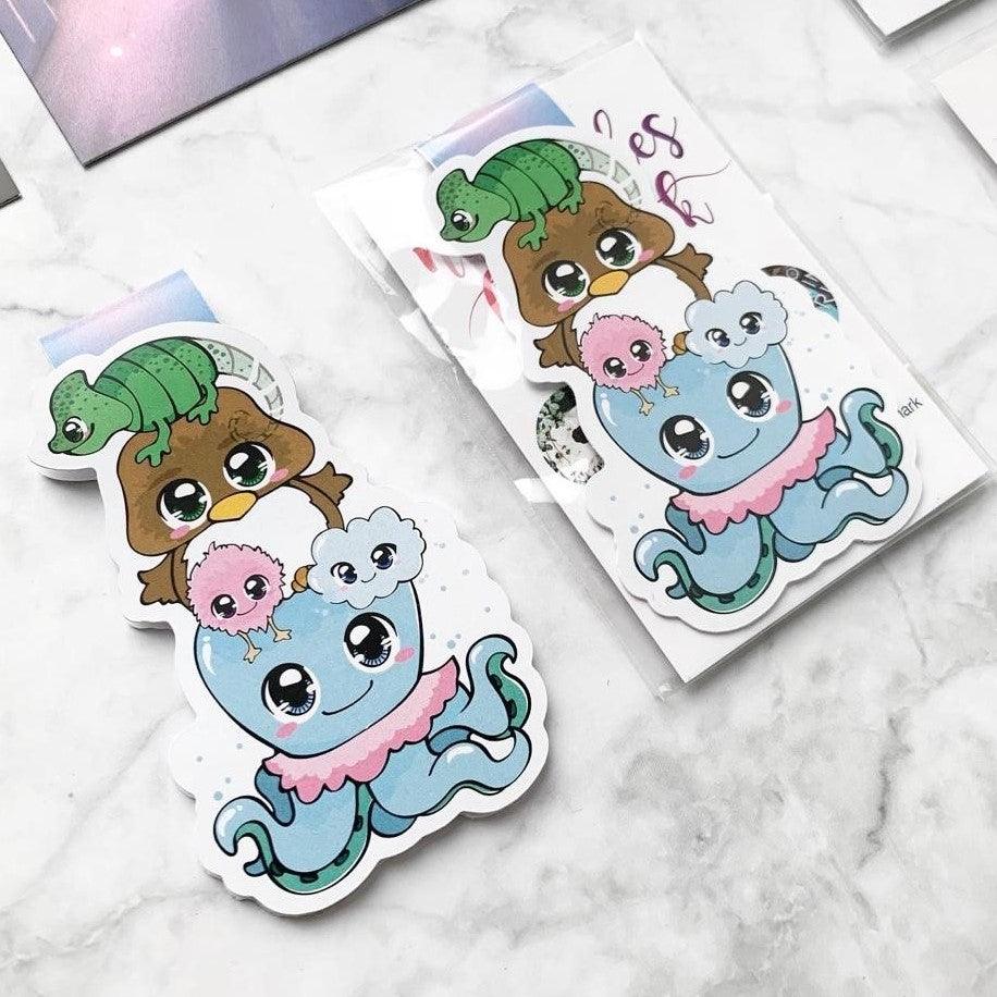 Das Produktbild zeigt ein Magnetlesezeichen mit fünf magischen Wesen aus dem Buch 