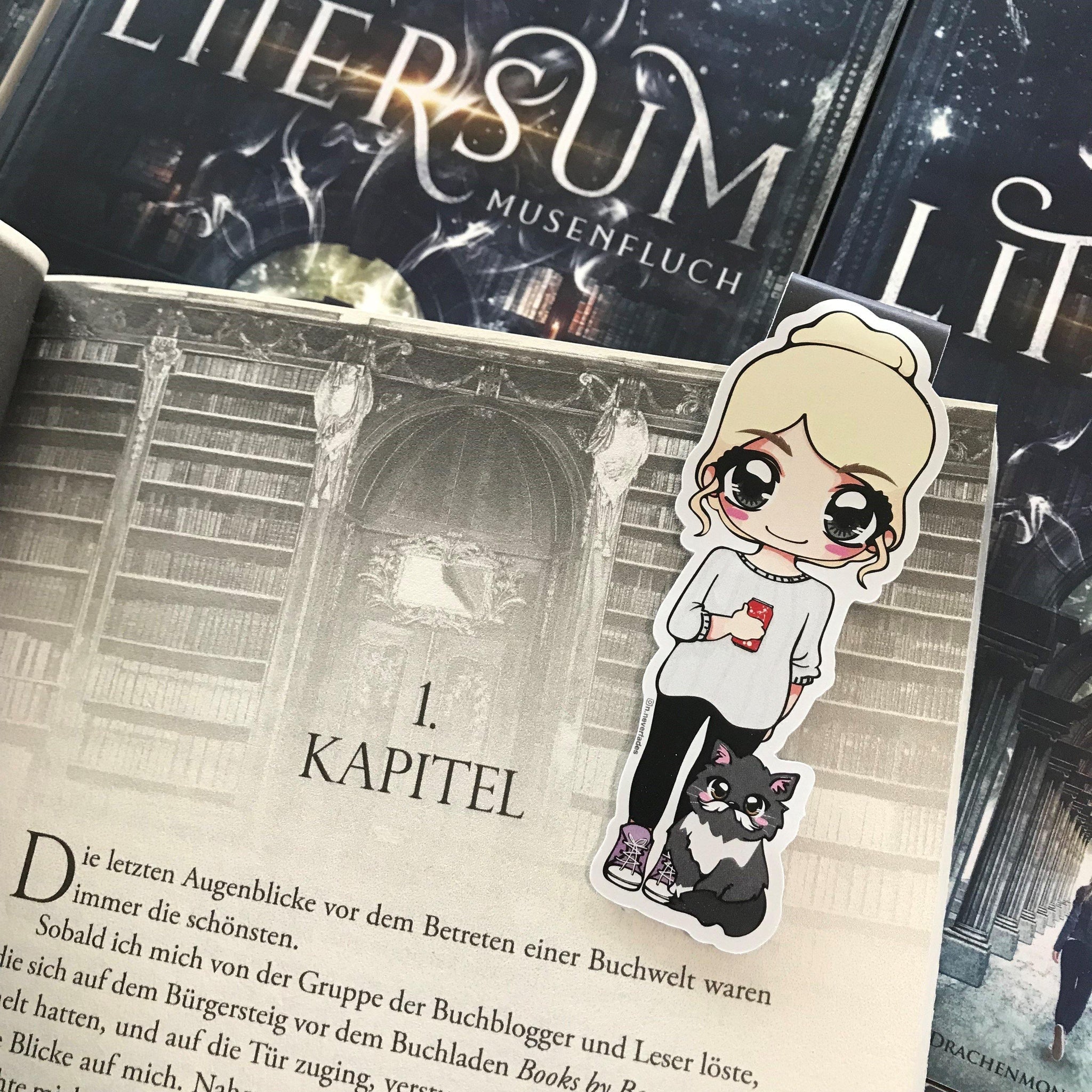 Das Produktbild zeigt ein Magnetlesezeichten mit einer blonden Frau. Sie trägt ein weißes Sweatshirt, eine schwarze Hose und grau-weiße Schuhe. In ihrer rechten Hand hält sie eine rote Getränkedose und neben ihr sitzt eine schwarz-grau-weiße Katze. Gezeichnet ist das Lesezeichen im Anime-Stil.